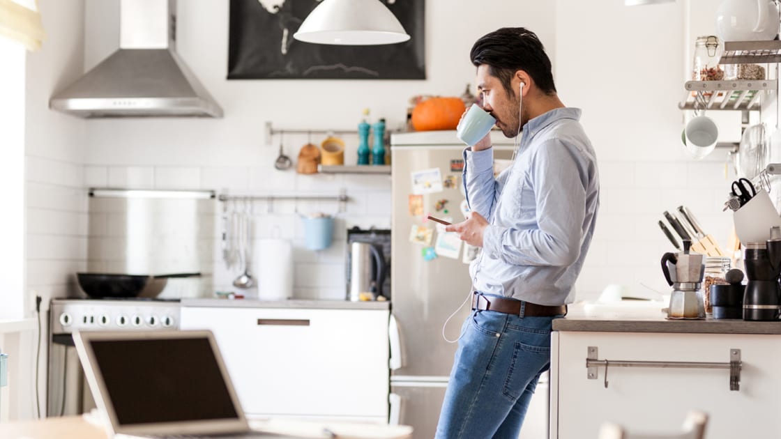 A man drinking coffee on his right hand and looking at his phone on his left hand