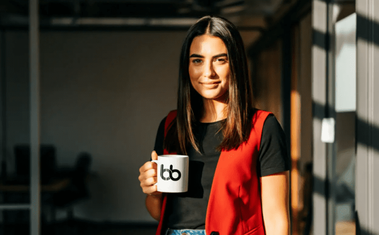 woman in black shirt and red sleeveless blazer holding a cup with baden bower logo.